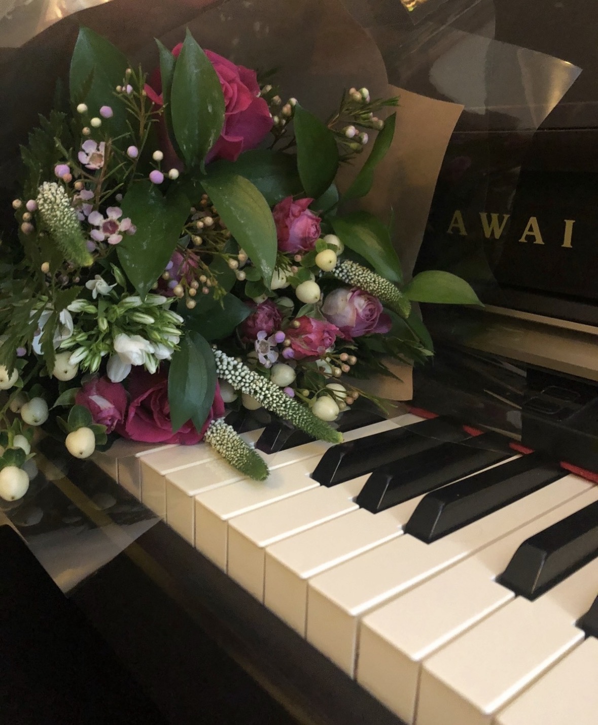 Flowers resting across the keys of a Kawai piano