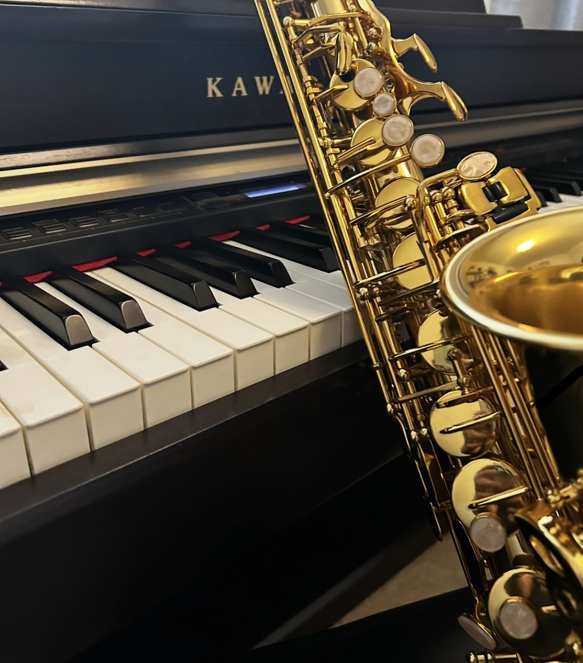 A gold saxophone beside a Kawai piano